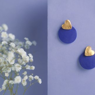 Orecchini artigianali blu con dettaglio a cuore dorato su fondo lilla