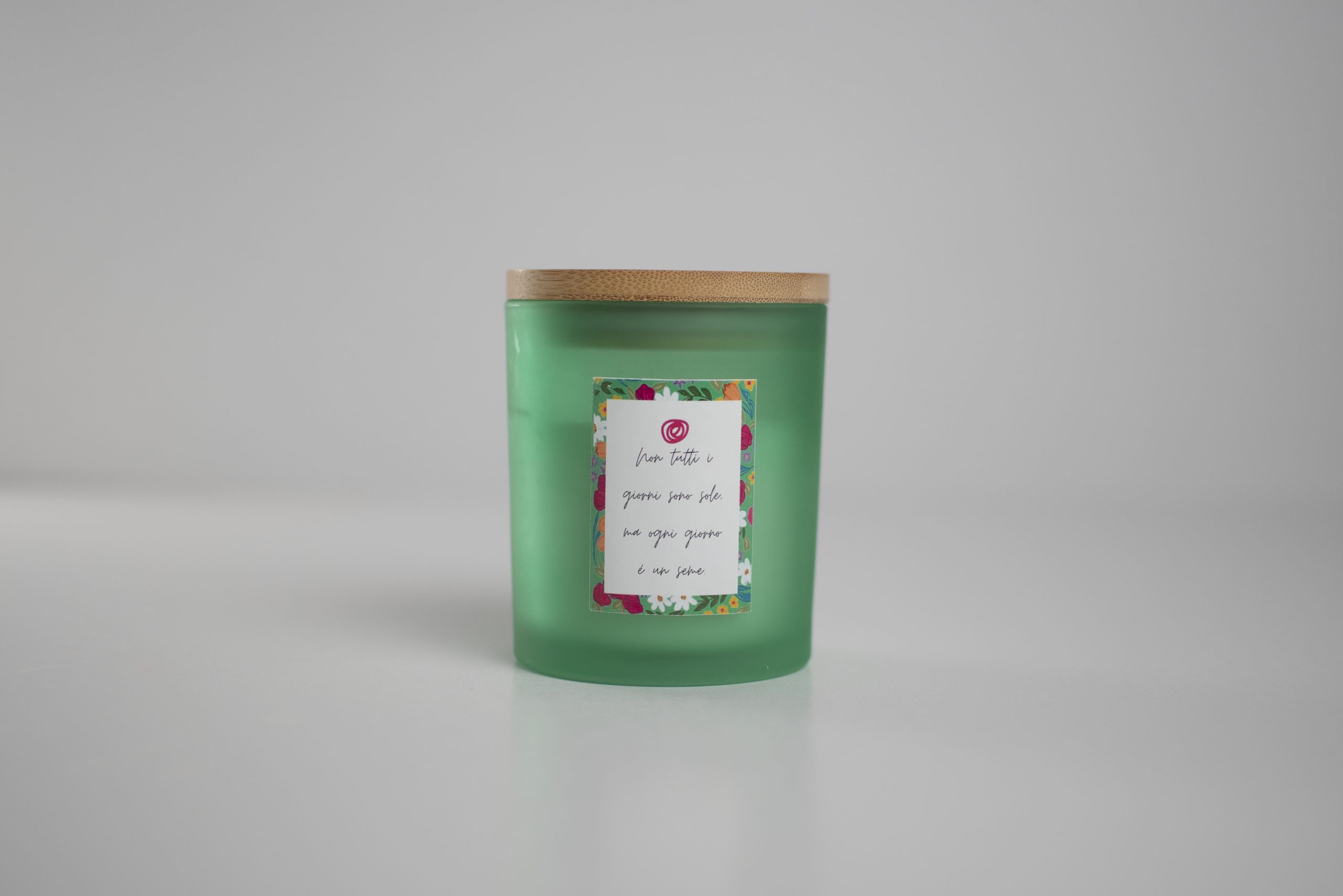 Candela artigianale verde in vetro satinato con coperchio in legno e etichetta floreale