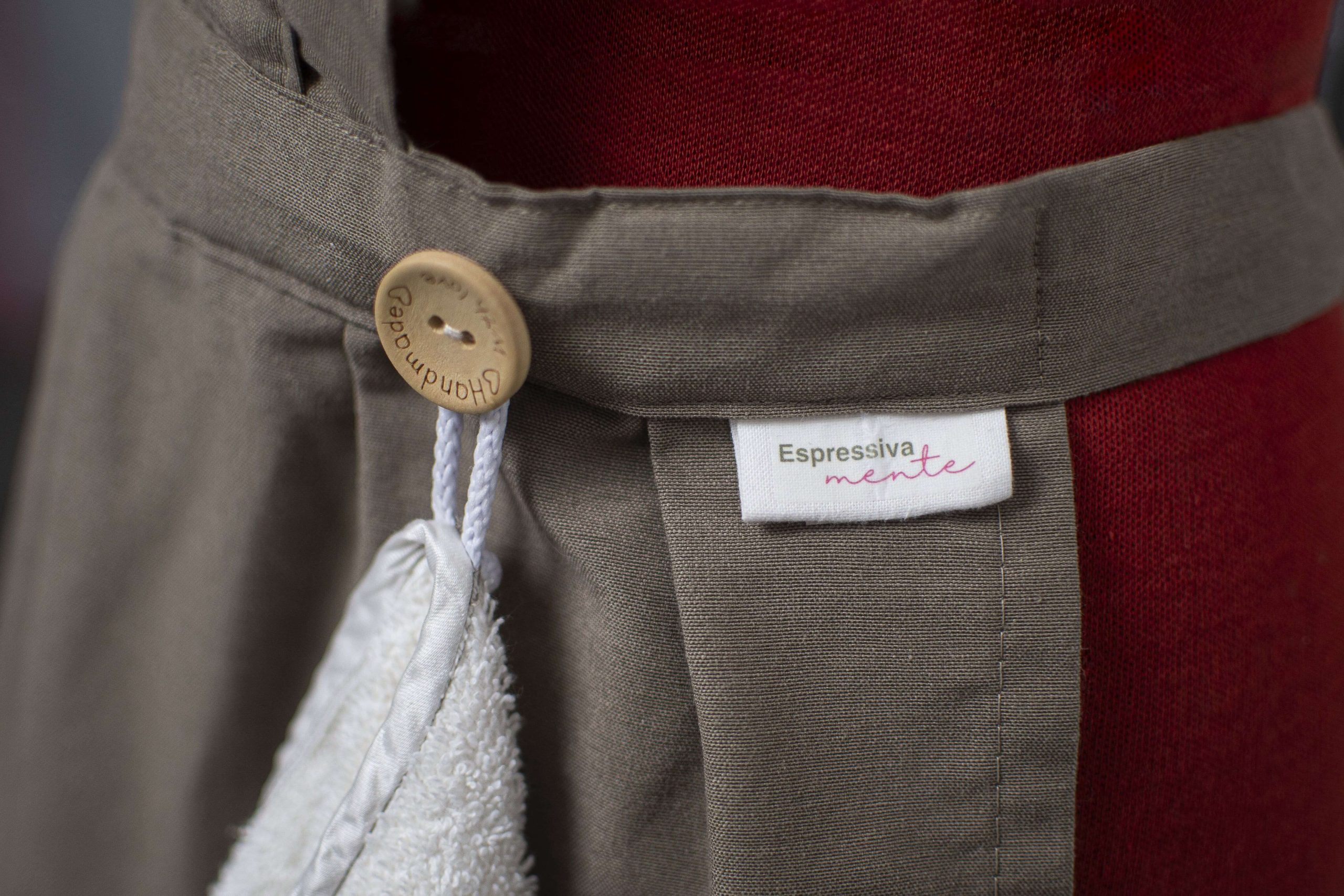 Grembiule artigianale in tessuto grigio con etichetta Espressivamente e bottone Handmade