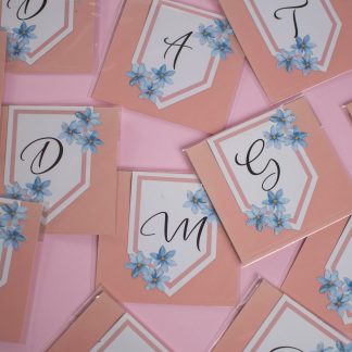 Cartoncini alfabetici decorati con fiorellini azzurri su sfondo rosa